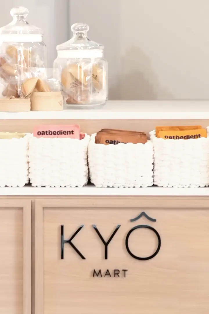 The KYÔ Mart counter in light oak with its logo, white woven baskets and jars of fortune cookies