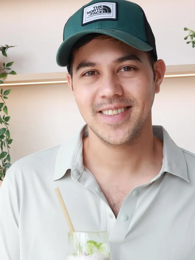 A smiling guest holding an iced matcha in a KYÔ cup