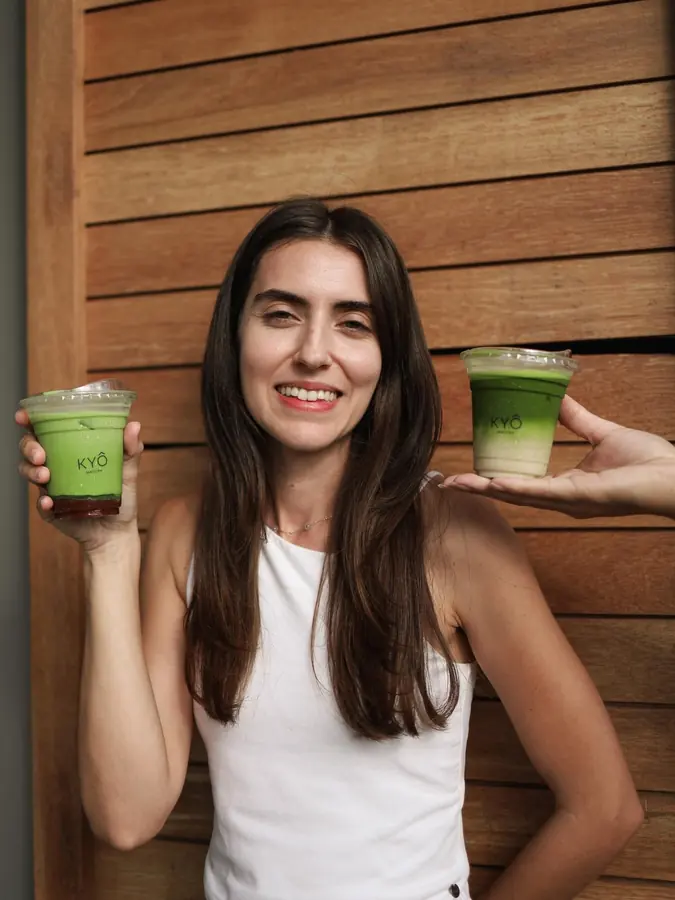 Two iced matcha lattes in KYÔ cups, held up in the light