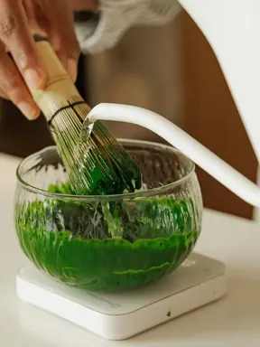 Hot water poured from a kettle into the bowl of matcha