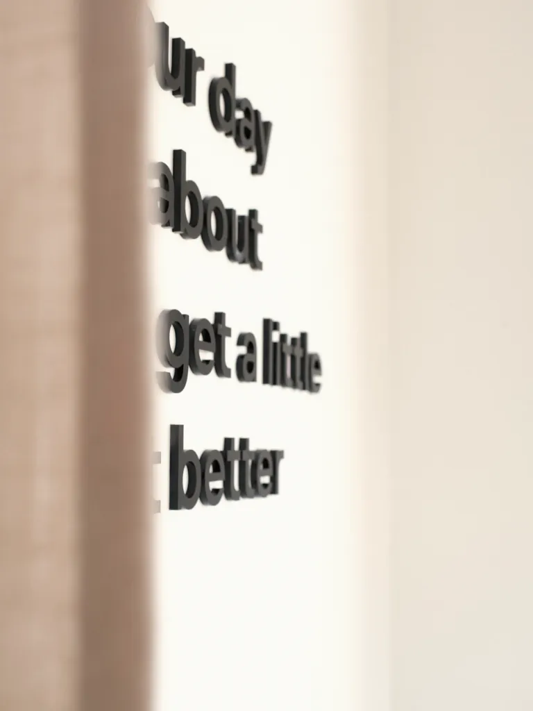 Black lettering on a white wall at KYÔ, partly hidden by a curtain